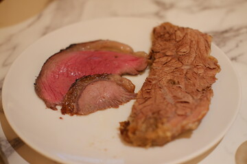 Sliced steak on a white plate, showing the texture and color.