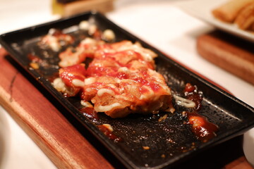 Close-up shot of a delicious fried food dish with sauce on a black plate