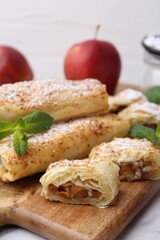 Tasty apple strudels with powdered sugar and mint on table, closeup