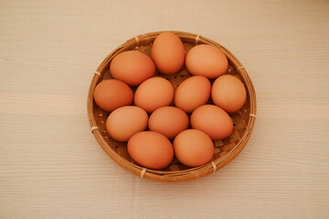 A basket filled with fresh brown eggs on a wooden table