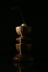 Extinguished candle in candlestick on mirror surface against black background