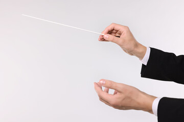 Conductor with baton on light grey background, closeup. Space for text