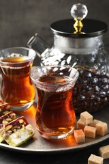 Tasty Turkish tea and delight on black table, closeup