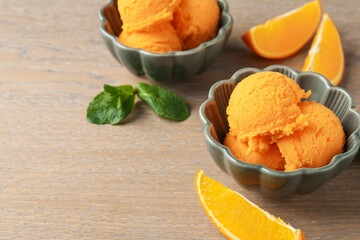 Tasty orange sorbet, fresh fruits and mint on wooden table, closeup
