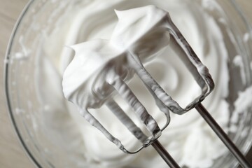 Hand mixer with whisks and whipped cream over bowl, top view