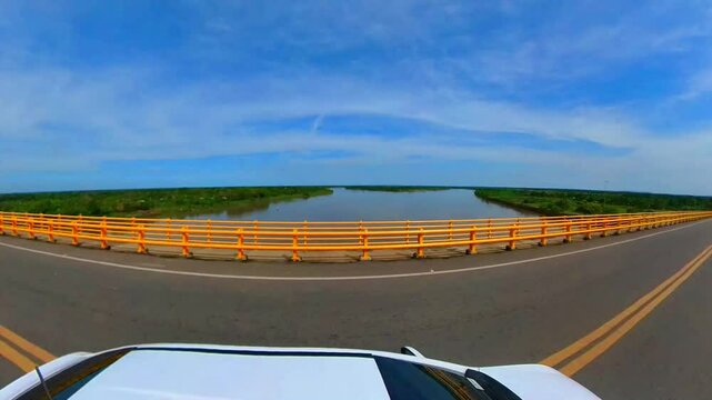 Crossing the Grand Magangue Bridge Towards Mompox in a White car, Enjoying the View of the Clear Blue Sky and a Branch of the Magdalena River Below