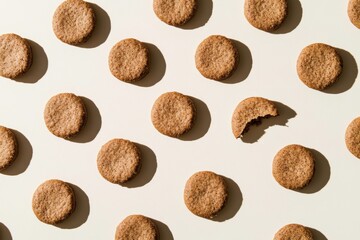 Top-down view of round buckwheat cookies arranged in a grid with strong shadows, featuring broken and bitten pieces for variation