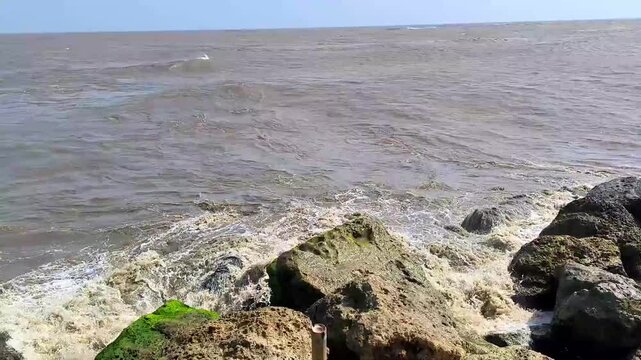 The ocean is calm and the rocks are grey. Puerto Mocho, Bocas de ceniza, Barranquilla, Colombia