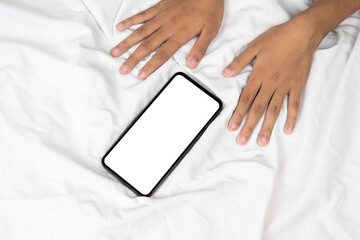 Smartphone mockup screen on white bed sheet, and the woman's hand beside him .top view flat lay