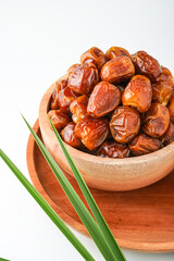 Dates fruit sukari or kurma sukari, in wooden bowl isolated on white background