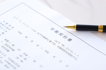 雇用者と労働者の間で労働契約書を交わす
