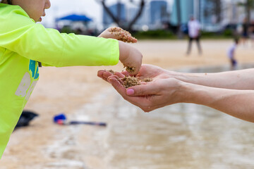 Child Sharing Sand with Adult Hands at a Honolulu Beach