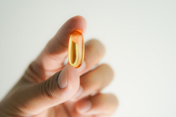 Male hand holding Oil filled capsules, softgel of food supplements, fish oil, omega 3, vitamin E