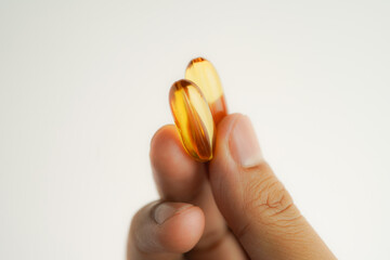 Male hand holding Fish oil capsules with omega 3, omega 9, vitamin D, vitamin E, Cod liver oil