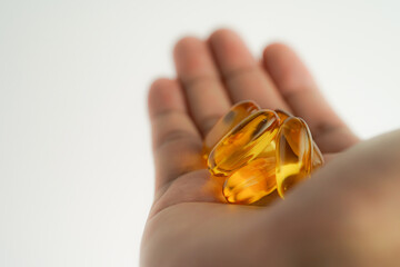 Male hand holding Fish oil capsules with omega 3, omega 9, vitamin D, vitamin E, Cod liver oil