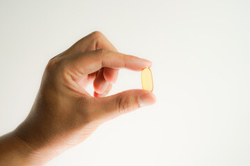 Male hand holding Fish oil capsules with omega 3, omega 9, vitamin D, vitamin E, Cod liver oil