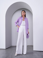 Elegant woman model showcases pastel fashion in a studio setting with modern architecture