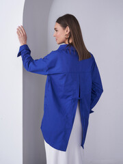 Model in a stylish blue shirt poses gracefully in a minimalist studio setting