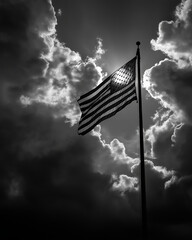 American Flag in the Sky: A dramatic, black and white image showcasing the American flag waving proudly against a dynamic, cloudy sky.