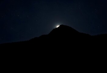 Moon rising over the mountain at night