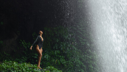 Woman in Bodysuit Embracing Jungle Waterfall Mist in Bali, Indonesia
