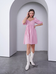 Captivating model in pink dress poses elegantly in a stylish studio setting
