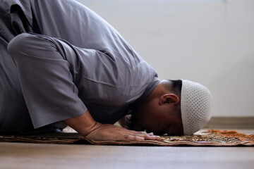 Fototapeta premium Side View Of Muslim Man Praying In Mosque With Prostration Salah Movement