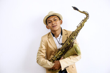 Naklejka premium Portrait Of Smiling Young Asian Man Holding Saxophone And Looking At Camera