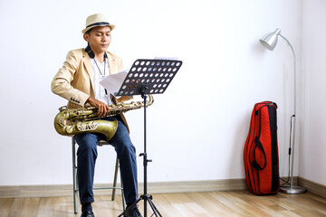 Portrait Of Young Saxophonist Man Preparing Musical Notes On Stand In The Studio