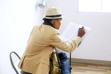 Portrait Of Young Musician Guy Playing Saxophone And Writing Down Ideas On Musical Notes