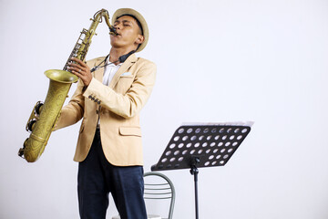 Portrait Of Young Asian Man Jazz Musician Playing Saxophone In Studio