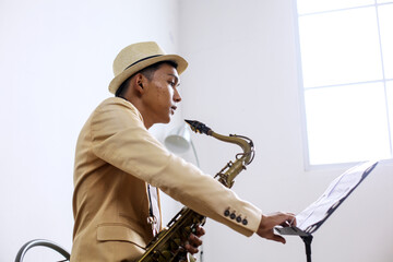 Saxophonist Male Playing According To Sheet Music In Studio