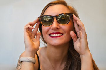 Naklejka premium Close-up portrait of a beautiful Latina blonde woman, posing confidently and smiling, wearing glasses and red lips with lipstick.