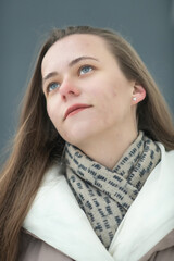 Portrait of a young beautiful long-haired girl in a winter coat outdoors.