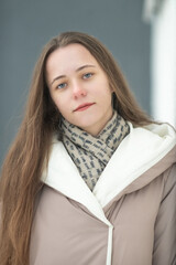 Portrait of a young beautiful long-haired girl in a winter coat outdoors.