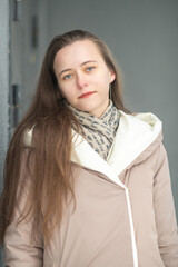 Portrait of a young beautiful long-haired girl in a winter coat outdoors.