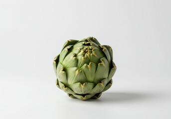 Fototapeta premium Single artichoke with green leaves sits centered on a white background in a studio shot with soft lighting