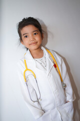 Little asian girl wearing a white coat playing doctor with holding a stethoscope in her hand. Perfect for themes related to education, creative play, and children's health.