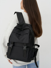 Fashion model showcases stylish black backpack in a modern studio setting