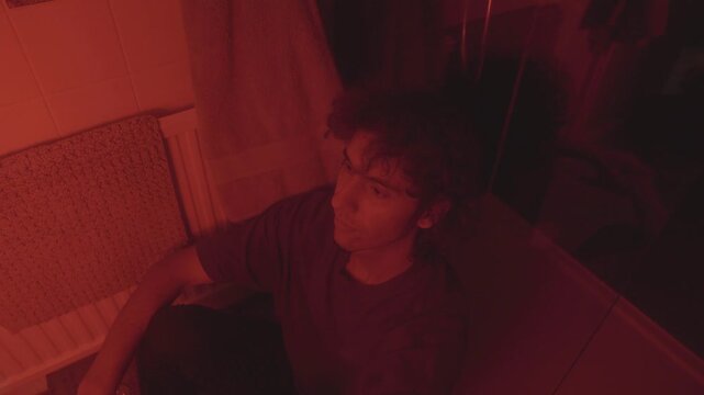 A Christian man in a bathroom, bathed in red lighting, reflects on his sin and spiritual struggle. The moody, emotional atmosphere symbolizes guilt, repentance, and introspection.