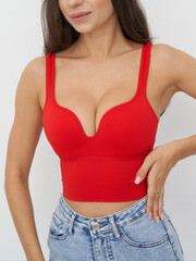 Elegant model poses in vibrant red top and denim shorts for a fashion studio shoot