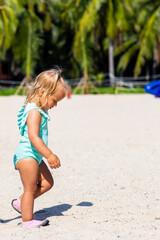 adorable caucasian baby girl walking on sandy beach at hot summer day. Child having fun during tropical vacation on sea in China