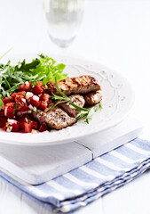 Fried pork tenderloin with tomato salsa. Bright background. Close up.	