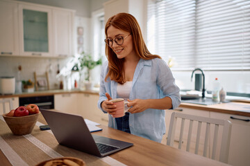 Happy woman reading email on computer while working at home.