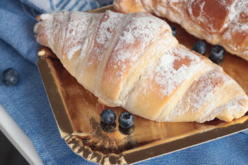 Croissant, brioche bun with powdered sugar and berries on blue linen napkin. Breakfast and food. 