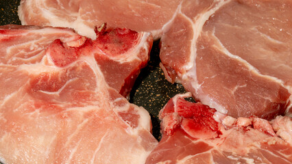 Raw pork chops glisten under kitchen lights, evoking gastronomic dreams of Carnivore Month and...