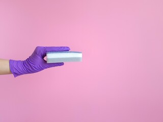 Housekeeping and hygiene concept. Hand in purple rubber glove holding porous sponge