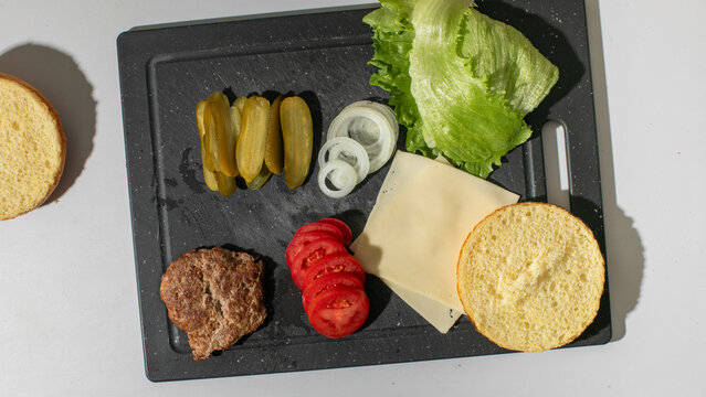 Assembling a deconstructed burger symphony, embodying National Cheeseburger Day and avant-garde culinary art with tactile precision