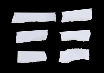 A set of irregularly shaped torn paper pieces arranged loosely over a black surface.