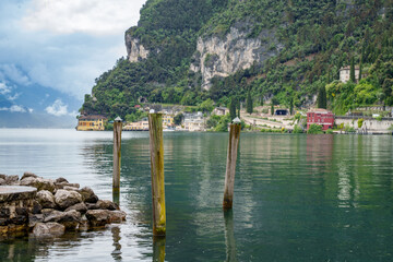 Rocks and weathered wooden pilings used for anchoring ships on the shore of Lake Garda, Italy....